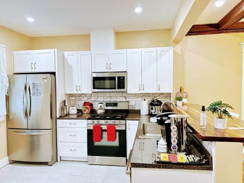 a kitchen with white cabinets and a stainless steel refrigerator at Linwood Paradise Home in Buffalo