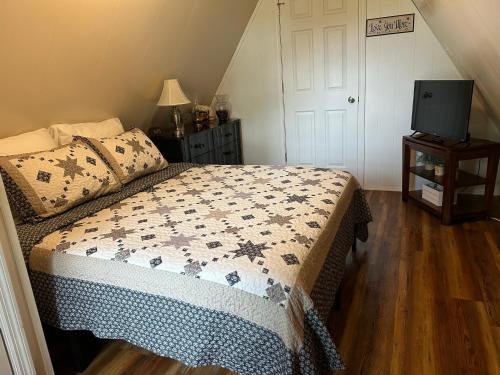 a bedroom with a bed and a tv on a wooden floor at Cherokee Cabin-Cave Run Lake and Cliff Views-Red River Gorge in Big Woods