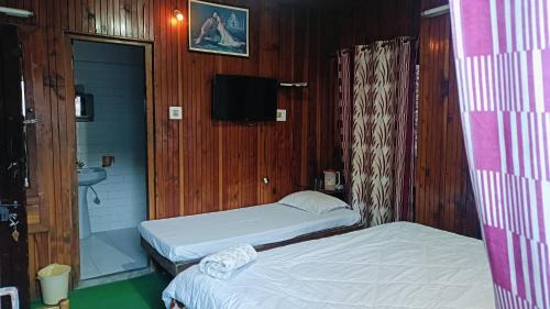 a room with two beds and a tv in it at Hotel Hema Holiday Home in Manāli