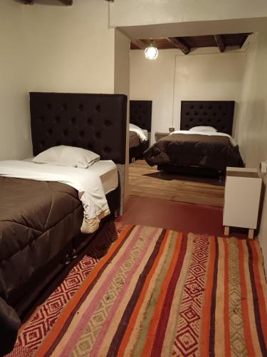 a bedroom with two beds and a rug at Auquis Hostel in Cusco