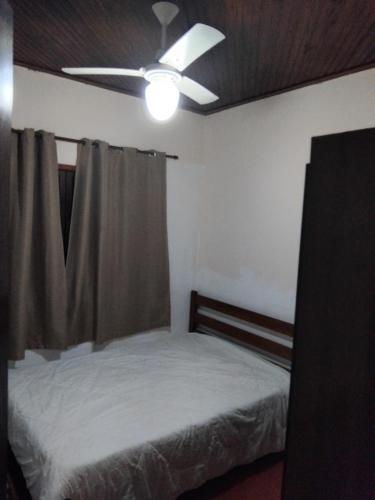 une chambre avec un lit et un ventilateur de plafond dans l'établissement Casa de praia, à Itanhaém