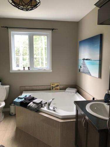 a bathroom with a tub and a sink and a window at Night Sky Cottage in Saint-Joachim