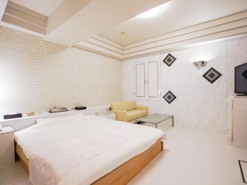 a white bedroom with a bed and a chair at Fun3 -Adult Only- in Yokohama