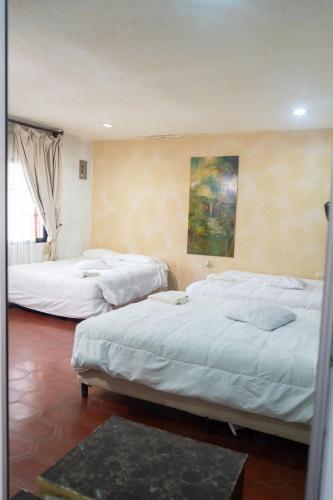 three beds in a room with a painting on the wall at Hotel Posada del Rey in Santa Cruz de Yojoa