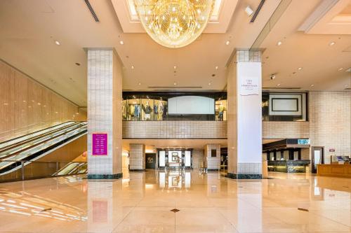 a large lobby with escalators and a chandelier at ANA Crowne Plaza Matsuyama by IHG in Matsuyama