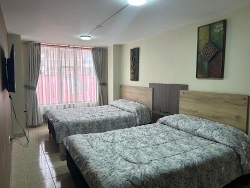 a hotel room with three beds and a window at Apartamento completo en el centro de Ipiales in Ipiales