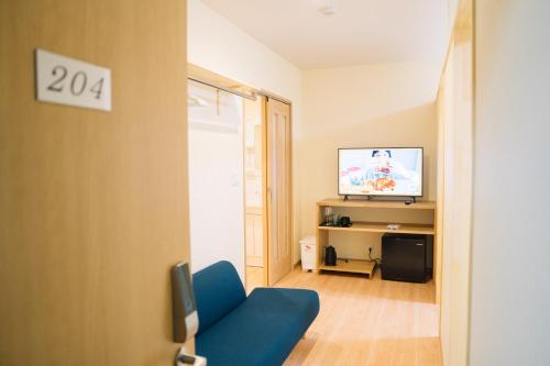 妙高市にあるMatsuya hotelの青いソファとテレビのあるリビングルーム