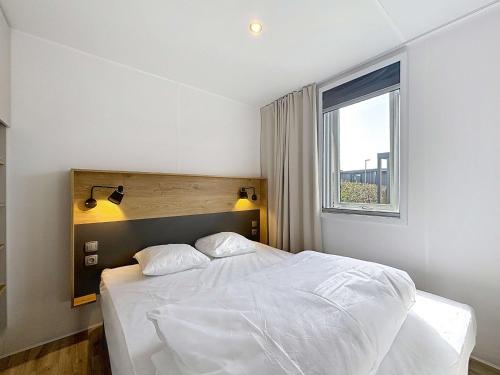 une chambre avec un lit blanc et une fenêtre dans l'établissement Mobil-home Grand Confort à Jullouville - Plage, Piscine Chauffée, Fitness et Parking - FR-1-361A-66, à Jullouville