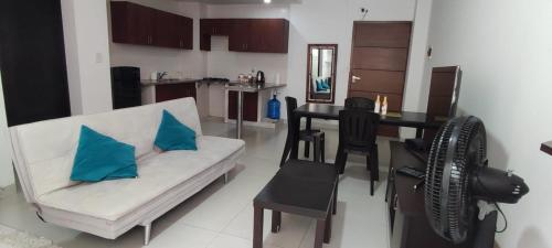 ein Wohnzimmer mit einem weißen Sofa und einem Tisch mit blauen Kissen in der Unterkunft Departamento Altos del Sur in Santa Cruz de la Sierra