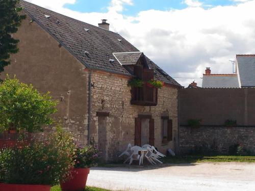 une maison en briques avec une table et des chaises dans la cour dans l'établissement Chambre d'hôtes avec petit-déjeuner inclus à Gidy - FR-1-590-452, à Gidy