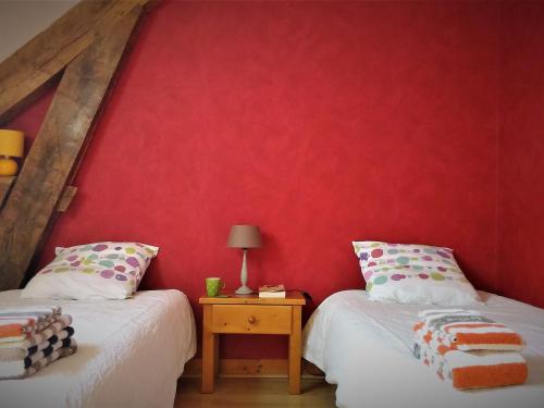 two beds in a room with a red wall at Chambre d'hôtes pour 2 avec salle d'eau privative et petit-déjeuner inclus - FR-1-590-464 in Gidy