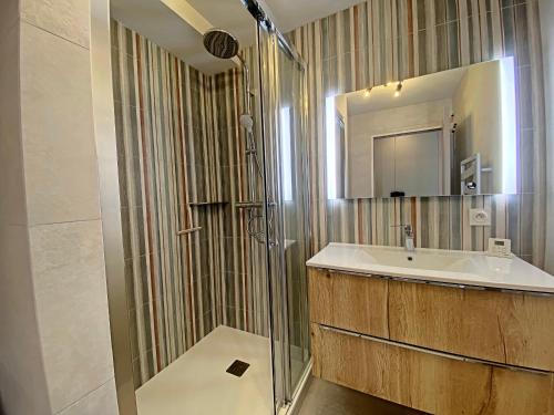 une salle de bain avec une douche, un lavabo et un miroir dans l'établissement Appart T3, terrasse, parking, 50m plage, proche commerces - FR-1-349-228, à Larmor-Plage