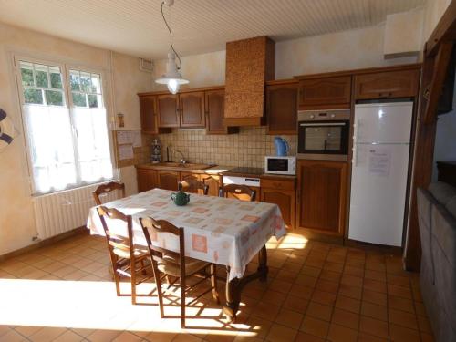 une cuisine avec une table avec des chaises et un réfrigérateur dans l'établissement Charmante maison à La Barre-de-Monts pour 4 pers - FR-1-540-320, à La Barre-de-Monts