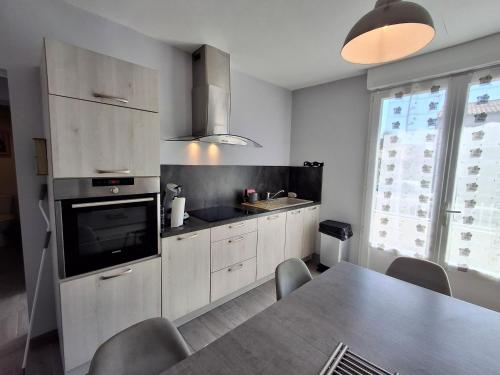 une cuisine avec une table à manger et une télévision dans l'établissement Maison plain-pied Châtelaillon-Plage à 500m de l'océan pour 6 pers, jardin, barbecue - FR-1-706-37, à Châtelaillon-Plage