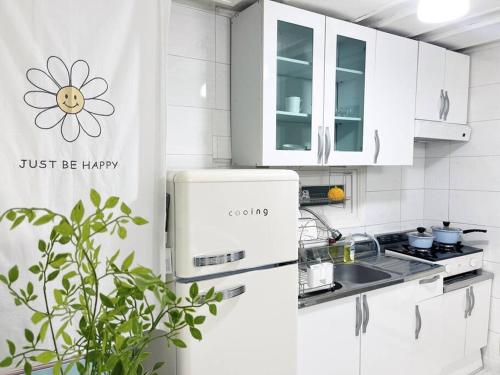 Una cocina blanca con una flor en la pared. en Cozy 2BR Netflix Metro 5min Jamsil,Gangnam, en Seongnam