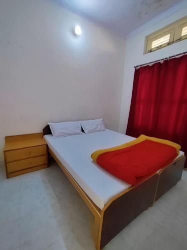 a bedroom with a bed with a red curtain at Mandakini Lodge And Restaurant in Ukhimath