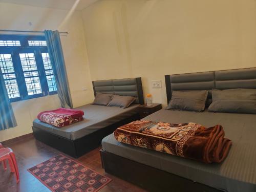 a bedroom with two beds and a window at Mandakini Lodge And Restaurant in Ukhimath