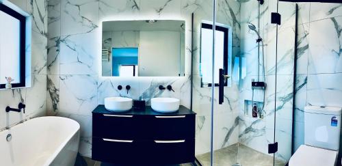 a bathroom with a sink and a mirror at Valley Sea View Villa Torbay in Auckland