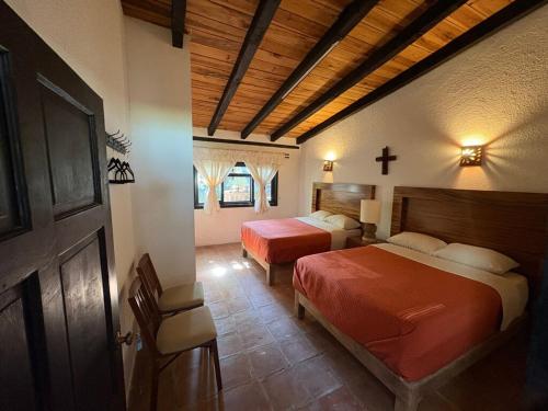 Un dormitorio con dos camas y una cruz en la pared. en Country house with unique view on Lake Pátzcuaro, en Tzintzuntzán