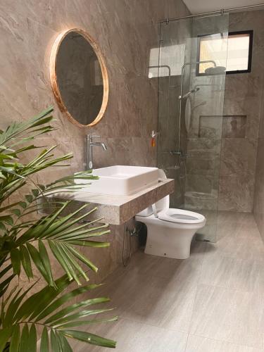 een badkamer met een wastafel, een toilet en een spiegel bij Villa Selah in Canggu