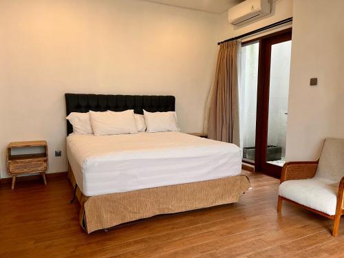 een slaapkamer met een groot bed en een stoel bij Villa Selah in Canggu