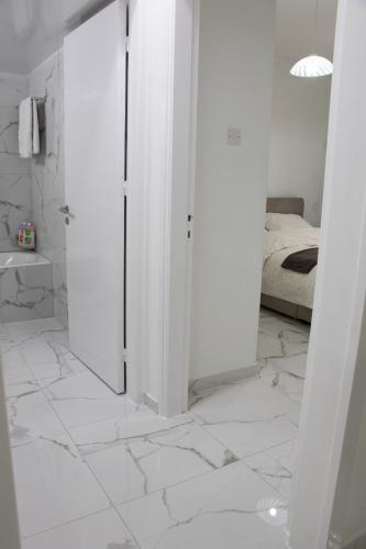 a white bathroom with a bed and a white tiled floor at Apartment,NEAR THE BEACH Pinikoudes in Larnaka