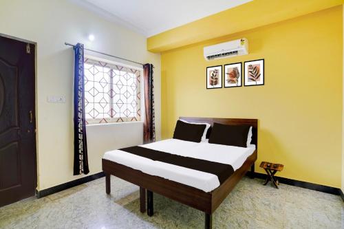 a bedroom with a bed and a yellow wall at Hotel O Shalom home stay in Goa