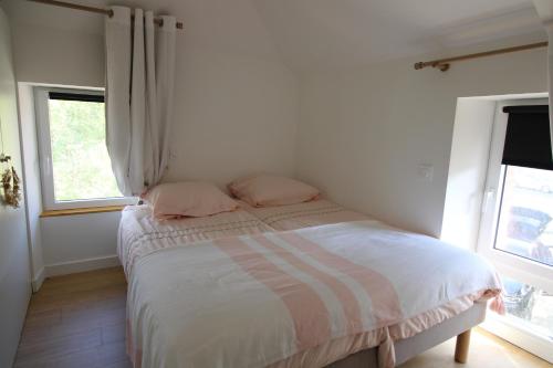 a bedroom with a bed with two pink pillows at Au petit jardin d Aizenay in Aizenay
