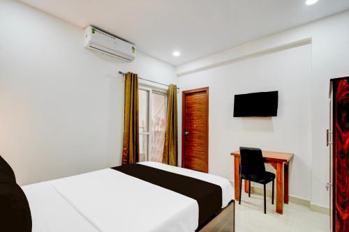 a bedroom with a bed and a desk and a television at Super Townhouse Nallagandla Nest in Hyderabad