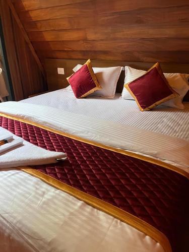 a large bed with red and white pillows on it at River Valley Huts, Wayanad in Panamaram