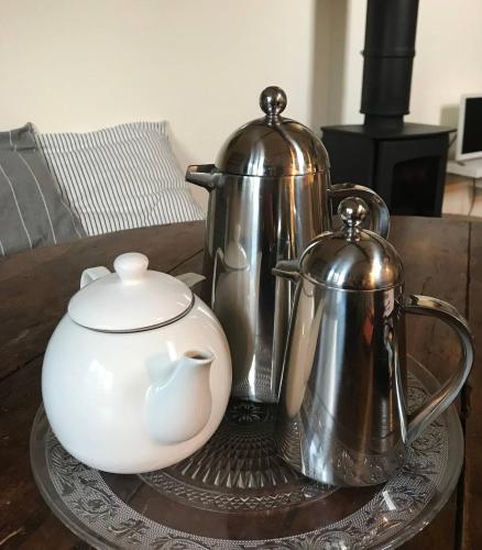 a table with two tea pots and a tea kettle at Stylish small barn near coast private garden Pass the Keys in Saint James
