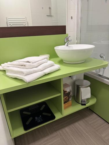 La salle de bains est pourvue d'un comptoir vert avec un lavabo et des serviettes. dans l'établissement Le Panorama, à Gréoux-les-Bains
