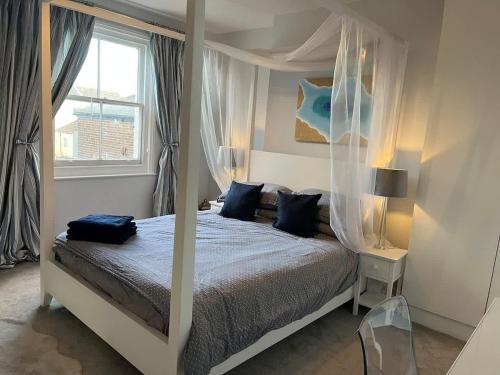 a bedroom with a canopy bed with blue pillows at Overlooking the sea - Spacious apartment in Littlehampton