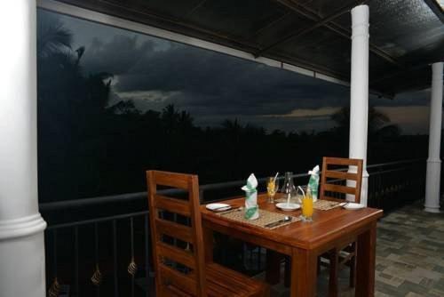 a wooden table with two chairs and a painting on a wall at Rajarata Family Resort in Anuradhapura