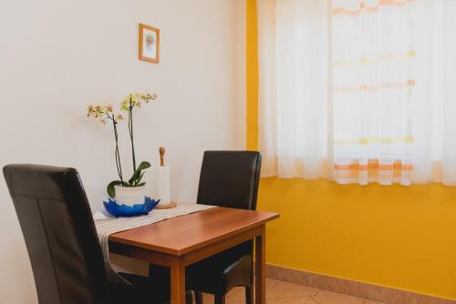 a dining room table with two chairs and a plant on it at Apartments Lovrić in Vodice