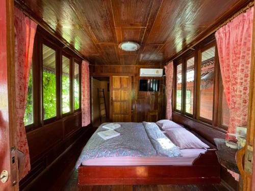 a bed in the middle of a room with windows at Healing House Holistic Farm Stay in Ban Wet