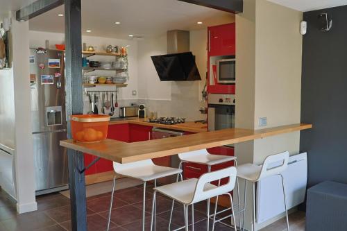une cuisine avec des placards rouges et des tabourets de bar blancs dans l'établissement Lepadaloft, à Villeneuve-Saint-Georges