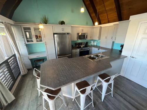 a kitchen with a counter with a sink and chairs at Ocean-View 1BR Condo on Black Sands Beach, Pool, Hot Tub in Pahala