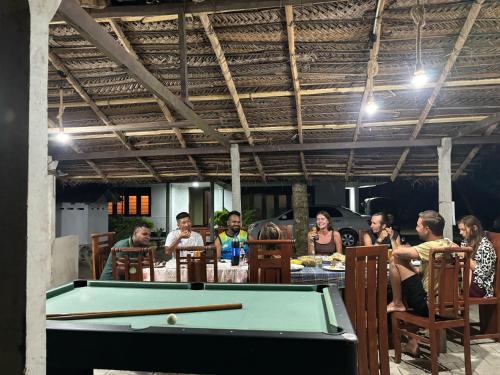 a group of people sitting around a pool table at Nature guesthous in Midigama