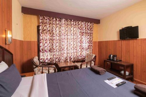 a hotel room with a bed and a window at Devi Enterprises - Hotel Khems in Ooty
