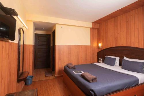 a bedroom with a large bed and a television at Devi Enterprises - Hotel Khems in Ooty