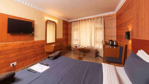 a hotel room with a bed and a flat screen tv at Devi Enterprises - Hotel Khems in Ooty