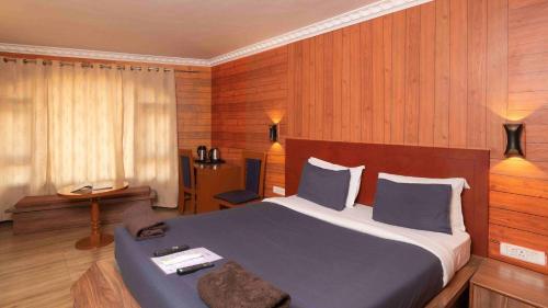 a bedroom with a large bed with wooden walls at Devi Enterprises - Hotel Khems in Ooty