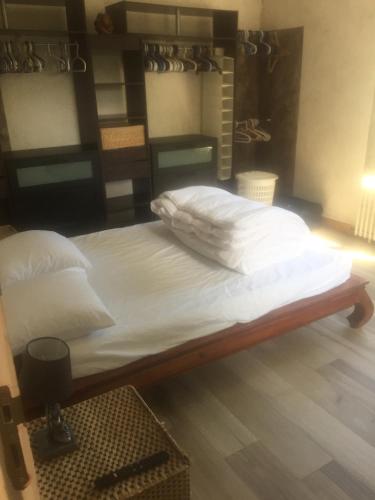 un lit avec des draps blancs et des oreillers dans une chambre dans l'établissement l'ensemblière, à Plérin