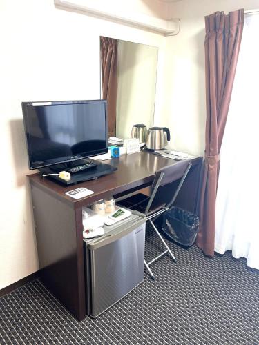 a desk in a hotel room with a television on it at Business Inn Sennichimae Hotel in Osaka