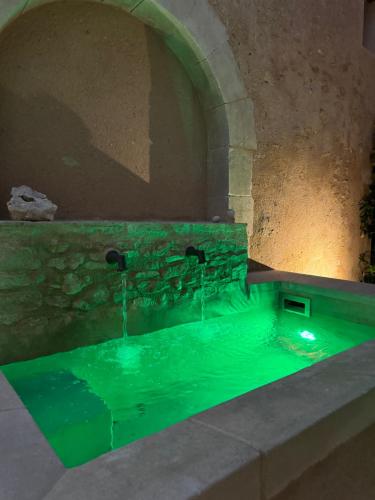 une fontaine d'eau avec éclairage vert dans une pièce en pierre dans l'établissement Atlantes de Saint Saturnin, à Saint-Saturnin-lès-Apt