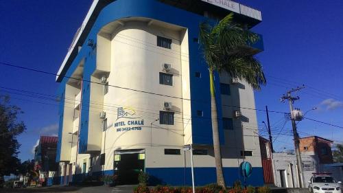 a white and blue building with a palm tree at Hotel Chalé Ji-Parana in Ji-Paraná