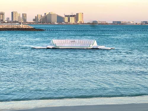 a boat in the water with a city in the background at Address Beach Resort Residences Bahrain in Manama