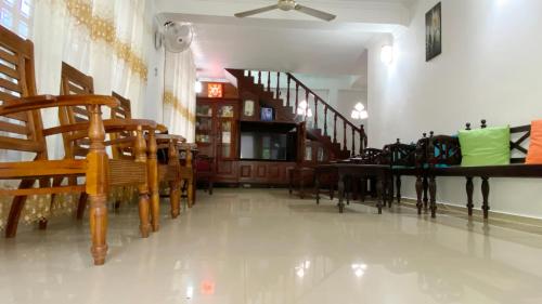 a living room with wooden chairs and a staircase at Jayamal Piyasa Apt in Ambalangoda