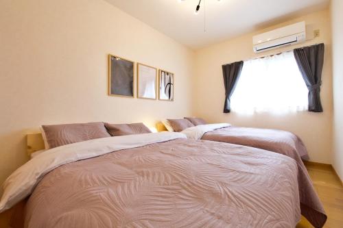 a bedroom with two beds and a window at ガネーシャ 501 in Tokeshi